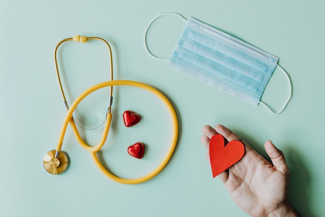 a mask paper heart and stethoscope on a blue background